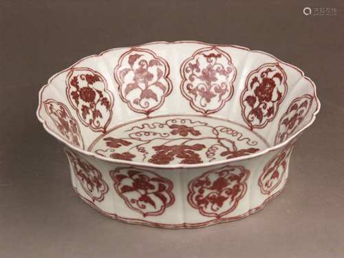 A red and white bowl for the Islamic market - China, Qing dynasty, of a round flower-like<br />shape, body facets slightly concave in the middle, partly incised vine and flower decoration in dark red paint, slightly worn, a blue retrospective 6-character kaishu mark ''Da Ming Xuande Nian Zhi'' in a double ring to the base, Dm.c.25,5cm