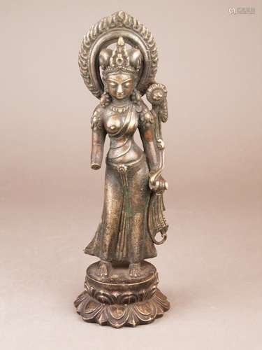 Standing Tara - Tibet / Nepal, 18th century, bronze, finely engraved, Tara standing in a<br />light tribhanga on a double lotus pedestal, the left hand holds the stem of a long flowering lotus plant, the right hand is missing, the long strands of hair are tied up to two elegant knots and crowned by a pointed high tiara, she wears large earrings and body jewelry, a flame aureole surrounds her head, dressed in a long dress, which is dotted with engraved lotus flowers, the left breast covered by a light cloth, weight ca. 1806g, height approx. 27cm, opened base