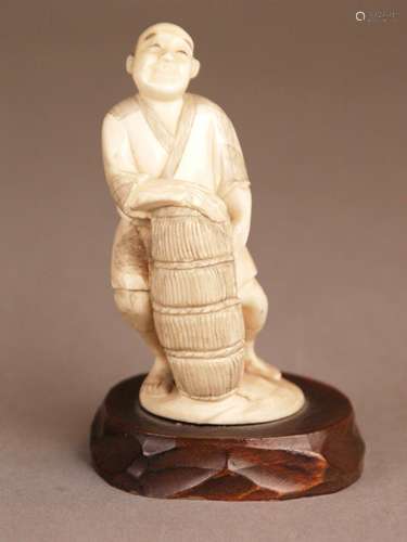 Okimono of a fisherman with basket - Japan, probably Meiji / Taisho period, ivory, carved,<br />robe with blacked ornaments, mounted on a wooden base, total height ca.9,5cm