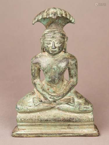 Jain Tirthankara Parshvanatha - India, yellow bronze, green patina, the 23rd of the 24<br />Tirthankaras siiting in padmâsana on a raised pedestal, hands in dhyana mudrâ, his head is shielded by a multi-headed serpent fanned like an umbrella, as all Jinas he is shown completely naked, on the center of his chest is a shrivatsa mark, incised inscription to the pedestal, open base, H.c.18,5cm, weight ca.2178g, Tirthankara (Tirtha = ford) are the Jain equivalents to Buddha depictions and are called ''Ford-maker'' = teacher /saviour,Parshvanatha was the first Tirthankara for whom there is historical evidence, but this evidence is intricately interwoven with legend, according to accounts in the Jain scripture Parshvanatha once saved a serpent that had been trapped in a log in an ascetic's fire, the snake, later reborn as Nagaraja Dharana, sheltered Parshvanatha from a storm sent by an evil demon