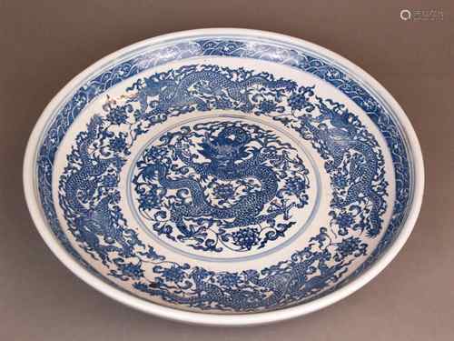 Large Chinese Porcelain Dragon Bowl - China, painted in underglaze blue: five-clawed<br />dragon in the midst of blooming lotus tendrils, corresponding dragon and wavy ornamental borders, underglaze blue Qing Qianlong mark in a double ring to the base, height c.7cm, diameter c.41cm, ca.3,8kg, partially worn, small glaze damage