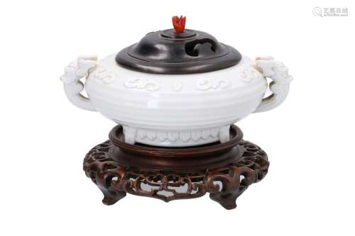 A blanc de Chine porcelain bowl with wooden base and cover, decorated in relief and two handles in