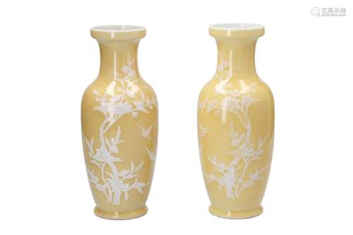 A pair of yellow glazed porcelain vases, decorated in white with flower branches and birds. Marked