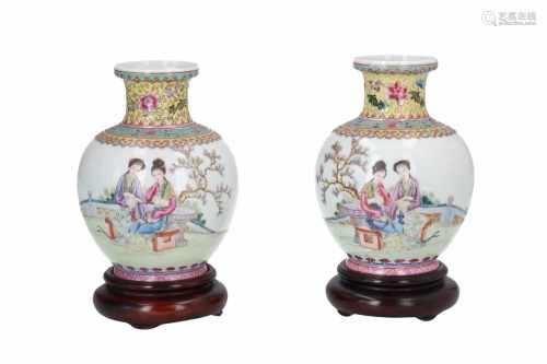 A pair of polychrome porcelain vases on wooden base, decorated with ladies in a garden and