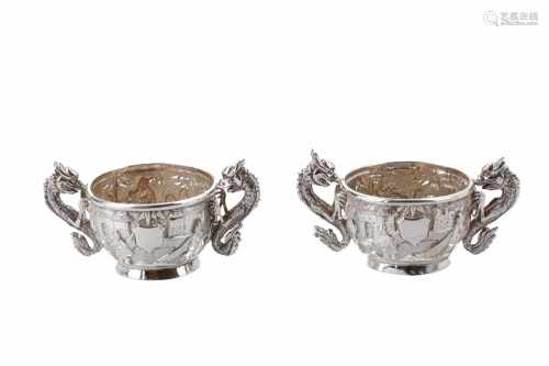 Two silver cups, decorated with figures amongst houses and gardens. Two handles on each cup, in