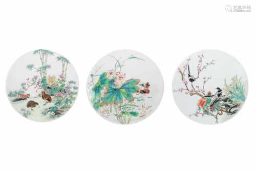 A lot of three round polychrome porcelain plaques, both decorated with flowers and birds.