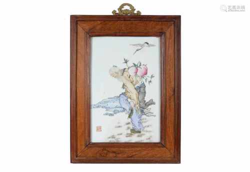 A polychrome porcelain plaque in wooden frame, decorated with flying crane and old man carrying