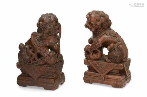 A pair of wooden sculptures depicting temple lions, one holding a ball, the other holding a cub. The