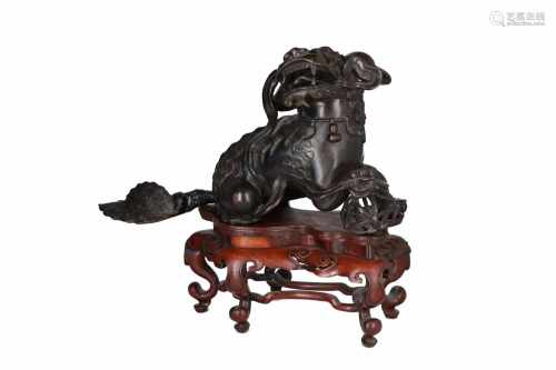 A bronze sculpture of a Fo-dog, on wooden base. China, 19th century. L. ca. 48 cm.