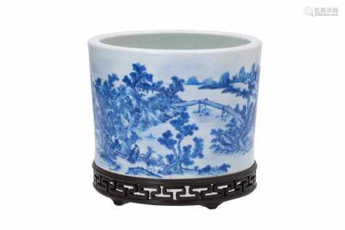 A round blue and white porcelain brush pot on wooden base, decorated with buildings in a river