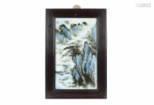 A polychrome porcelain plaque in wooden frame, depicting a mountainous landscape and characters.