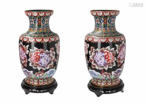 A pair of polychrome cloisonné vases on wooden bases, decorated with flowers. Both unmarked.