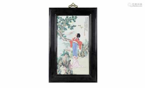 A polychrome porcelain plaque in wooden frame, depicting a lady under a tree, birds and