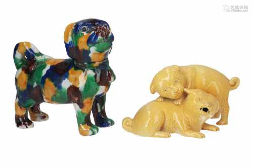 Lot of two porcelain sculptures, depicting 1) two yellow glazed dogs. L. 18,5 cm. 2) a spinach-and-