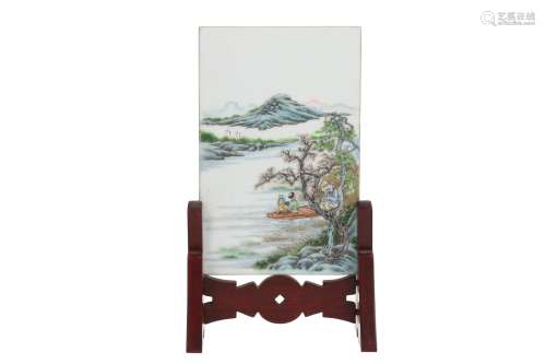 A polychrome porcelain plaque in wooden stand, depicting a river landscape with figures and a