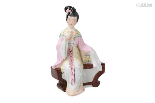 A polychrome porcelain sculpture of a lady on a bench, reading a book. Marked. China, 20th