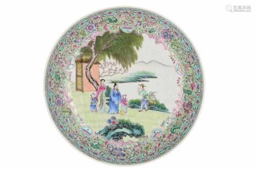 A polychrome porcelain deep dish, decorated with flowers and figures in a garden. Marked with seal
