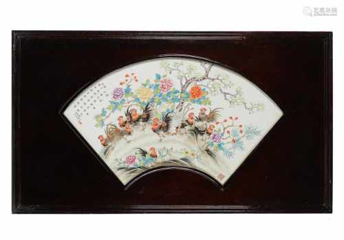 A fan shaped polychrome porcelain plaque in wooden frame, depicting roosters, flowers and a poem.