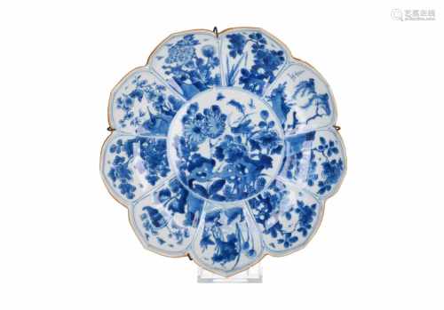 A blue and white porcelain dish with scalloped rim, decorated with flowers, birds and insects.