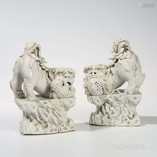 Pair of Blanc-de-Chine Foo Dogs, China, 20th century, standing on a rockwork base, both with their bottoms and tails up, their heads on