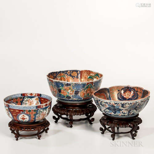 Large Three Imari Bowls and Wood Stands, Japan, one with barbed rim and a garden scene roundel to well, the base with double foot rings
