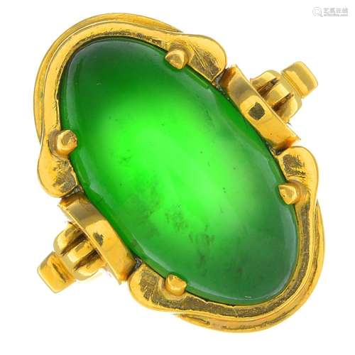 A jade ring. The oval jadeite cabochon, with grooved scroll surround and geometric shoulders.