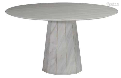 A wide round marble dining table on a central poly…