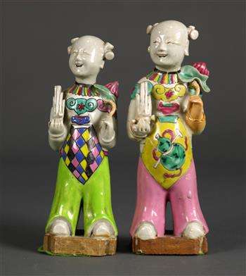 Pair of Chinese porcelain figures, each in the form of a child holding a sheng flute and a lotus