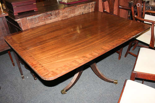 A mahogany rectangular breakfast table with crossbanded top, on pedestal support with three fluted