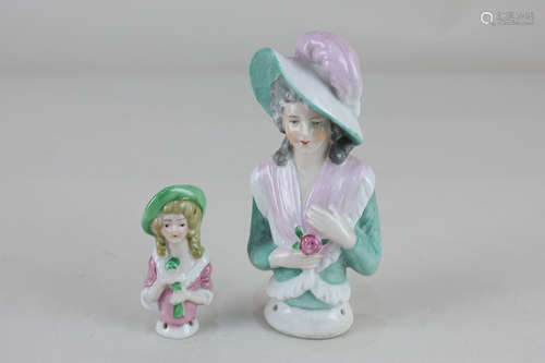 A porcelain half doll of a lady wearing a feathered hat and pink shawl, 12.5cm, and another similar,