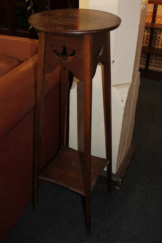 An oak jardiniere with circular top and pierced decoration, with undershelf, on square tapered legs,