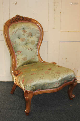 A Victorian button back nursing chair with foliate carved surmount and green and pink floral