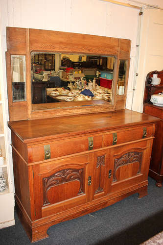 An Arts and Crafts Liberty style carved oak sideboard with two drawers with brass ring and strap