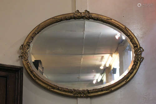 A giltwood and gesso oval wall mirror with ribbon and bow decoration, glass 54cm by 78cm