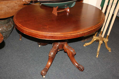 A Victorian oval drop leaf table, on turned pedestal and four foliate carved scroll legs, with