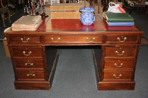 A large oak pedestal desk with red leather inset rectangular top above an arrangement of nine