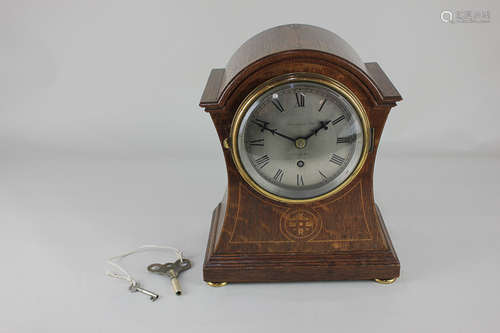 A 19th century inlaid oak waisted case mantel clock, the circular silverised dial marked Finnigans