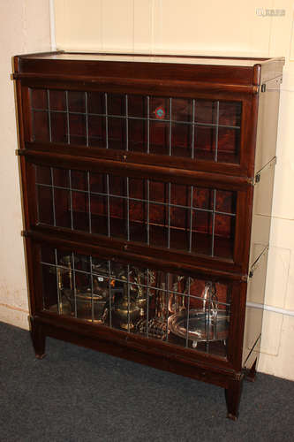 A Globe Wernicke mahogany three-tier bookcase with lead glazed panel sliding doors, on tapered feet,