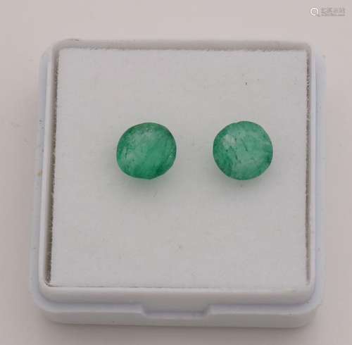 Two round faceted emeralds, ø 6.2 mm, with woolly green