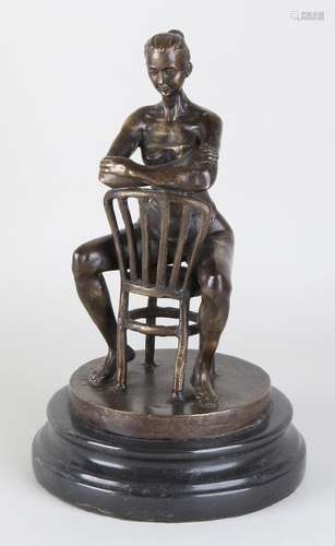 Bronze woman with corset on chair. Placed on a marble