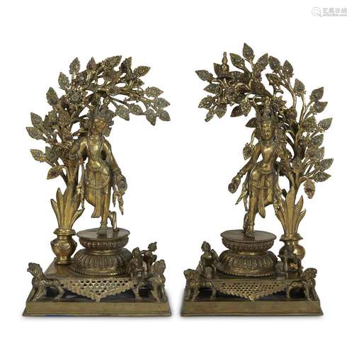 A PAIR OF NEPALESE BRASS ALTAR ORNAMENTS DEPICTING FEMALE DEITIES UNDER A FLOURISHING PLANT