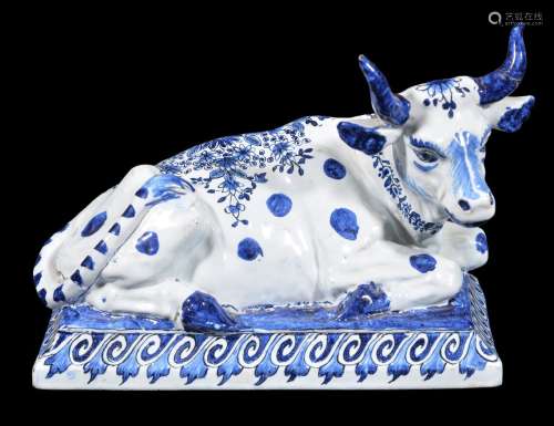 A Dutch Delft blue and white model of a recumbent cow, circa 1900, the underside with 'De Griekshe