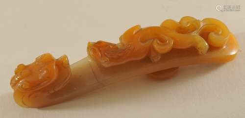 Jade garment hook. China. 19th century. Stone of an amber colour. Surface carved with chih lung and dragon finial. 3-1/2