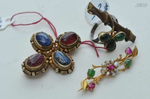 Lot of three pieces of jewelry. China. 19th to early 20th century. A Vermeil pendant set with rubies and sapphires, a pin set with rubies, jade and pearls and a bamboo shaped ring set with jade.