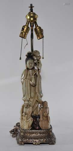 Three soapstone carvings. China. 19th century. Figures of Kuan Yiun and two of Shao Lao. Altogether mounted as a lamp. Overall height- 24