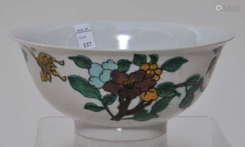 Porcelain bowl. China. 19th century. San Tsai decoration of flowers and butterflies in green, aubergine yellow and blue on a hua engraved ground of dragons. K'ang Hsi mark. 6