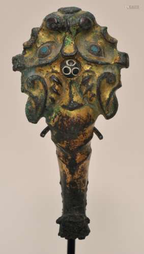 Gilt bronze garment hook. China. 3rd BC Ordos style. Lion mask with a dragon finial. Inlays of turquoise and black and white coloured glass. 5-1/4
