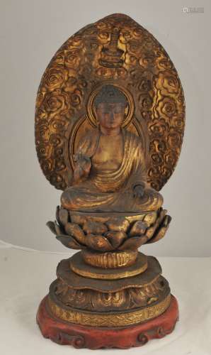 Carved wooden image of Buddha. Japan. 19th C. Seated figure of Amita on lotus throne with flame halo on back. Surface lacquered in gold, red, and black. Damage present. 21”H x 11”W.