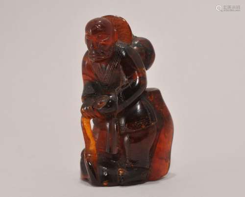 19th/20th century Chinese carved amber standing figure of a man holding a staff. Vase broken on his back. 2-3/4