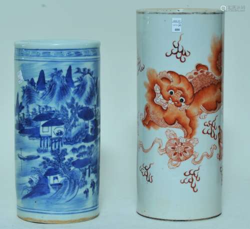 Lot of two porcelain hat stands. China. Early 20th century. Cylindrical form. One with a landscape in underglaze blue; the other with iron red foo dogs and brocade spheres. 9-3/4